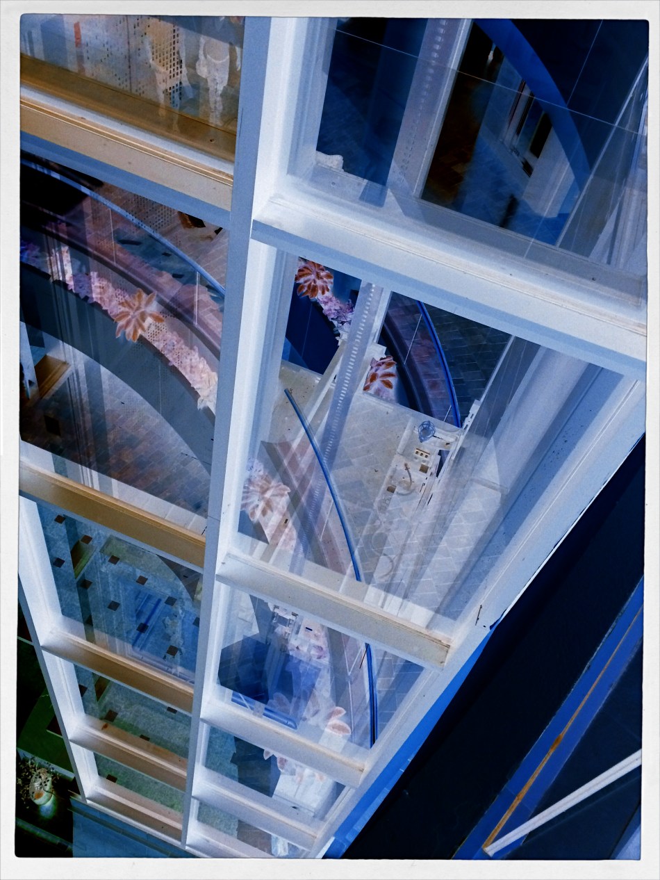 A glass elevator at a shopping mall, converted to a negative, then a fake Technicolor filter in a matters of seconds, via phone app.